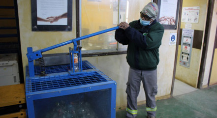 Imagen de una compactadora de botellas y un trabajador